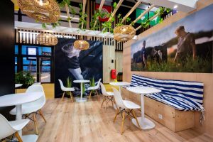 Stand sur mesure Arla Food, avec espace de convivialité, mobilier en bois, végétation et grandes images illustrant l’univers de l'agriculture.
